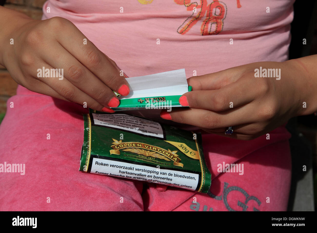 A teenage girl rolling her own cigarette with loose tobacco and rolling paper Stock Photo