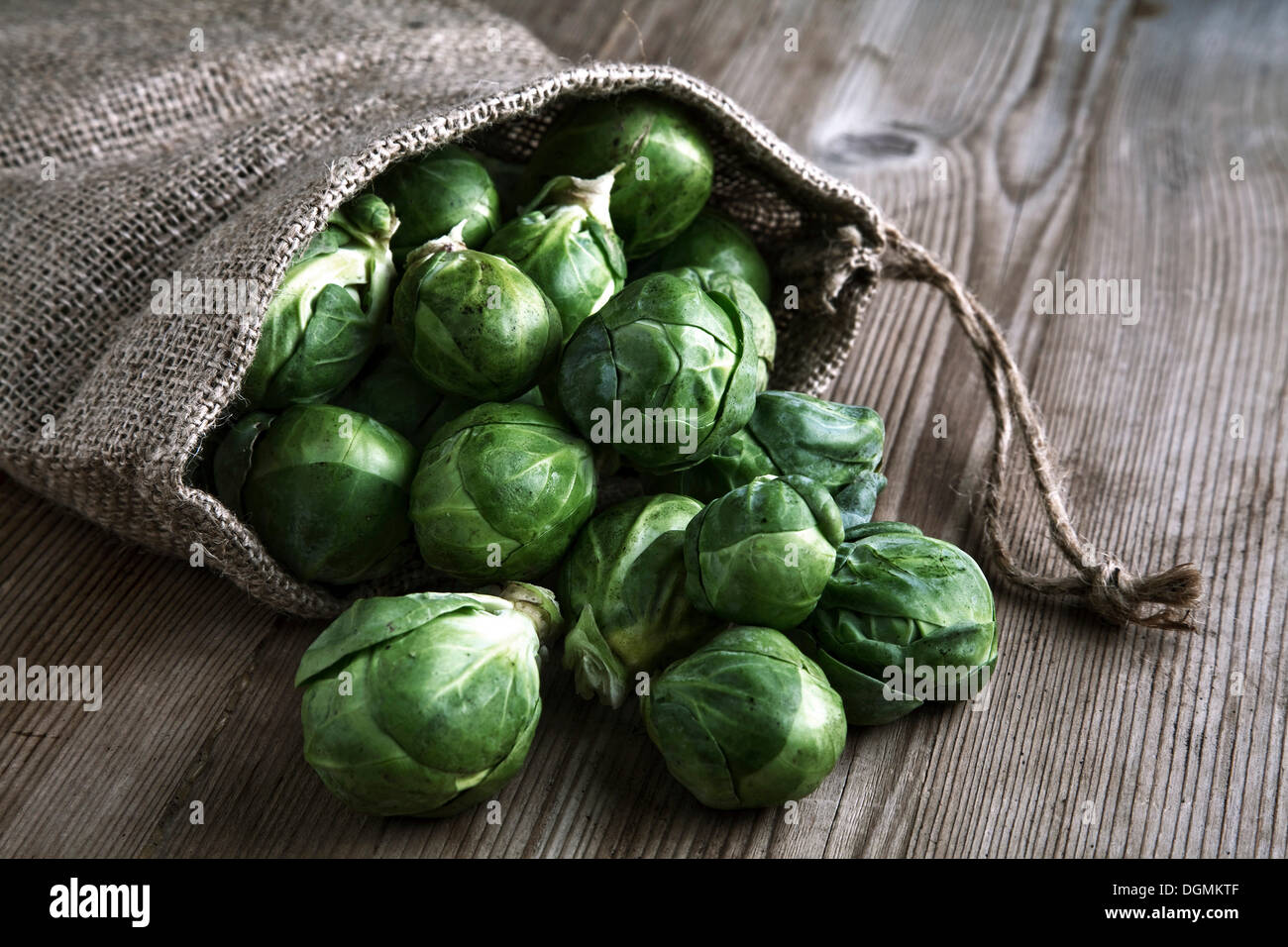 Organic Brussels sprouts in a jute sack on a wooden surface Stock Photo