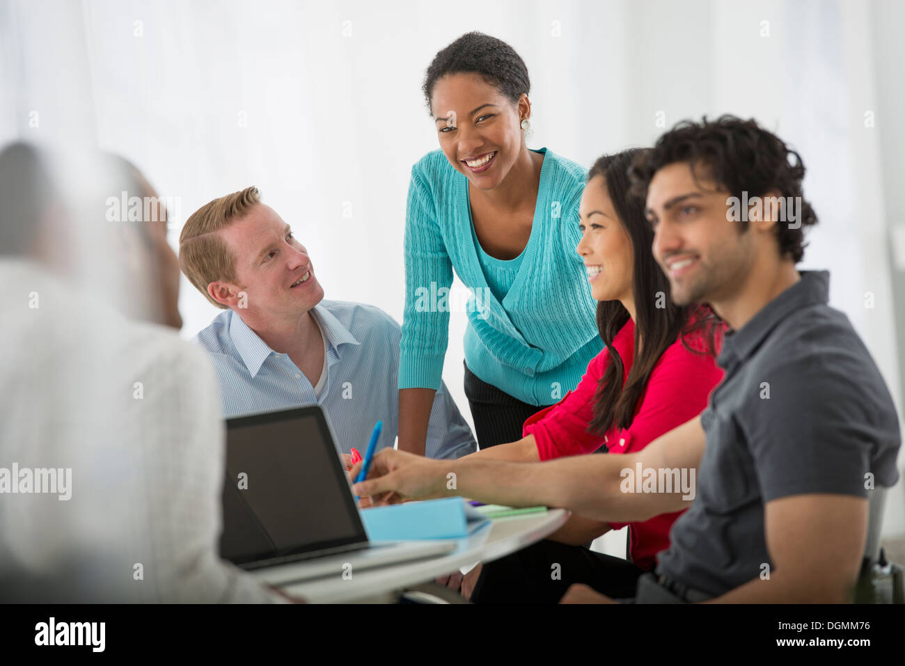 A multi ethnic group of people around a table, men and women. Teamwork. Meeting. Stock Photo