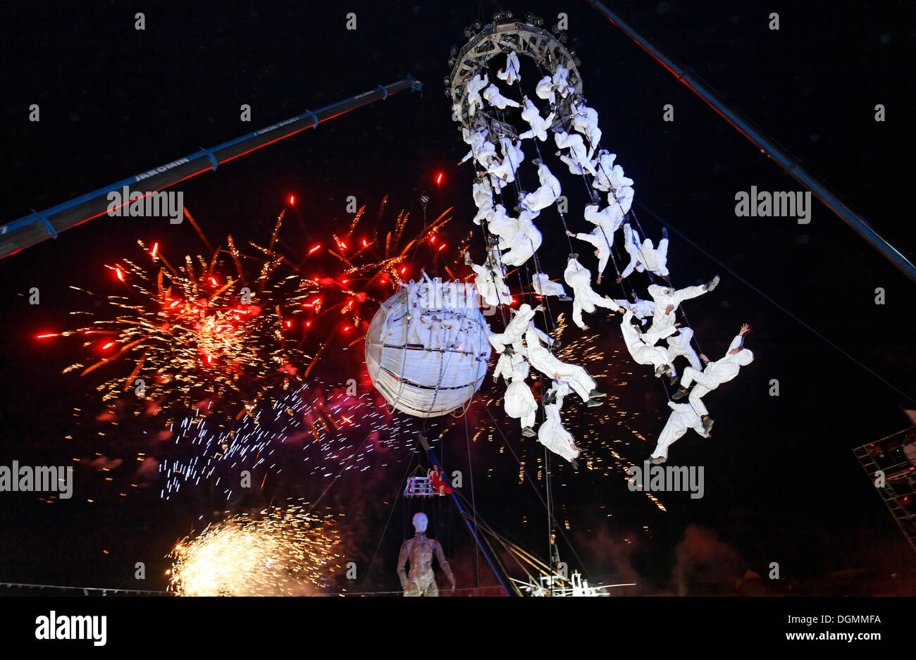 White-clad trapeze artists and globe floating in the sky, Global Rheingold, open-air theater by La Fura dels Baus Stock Photo