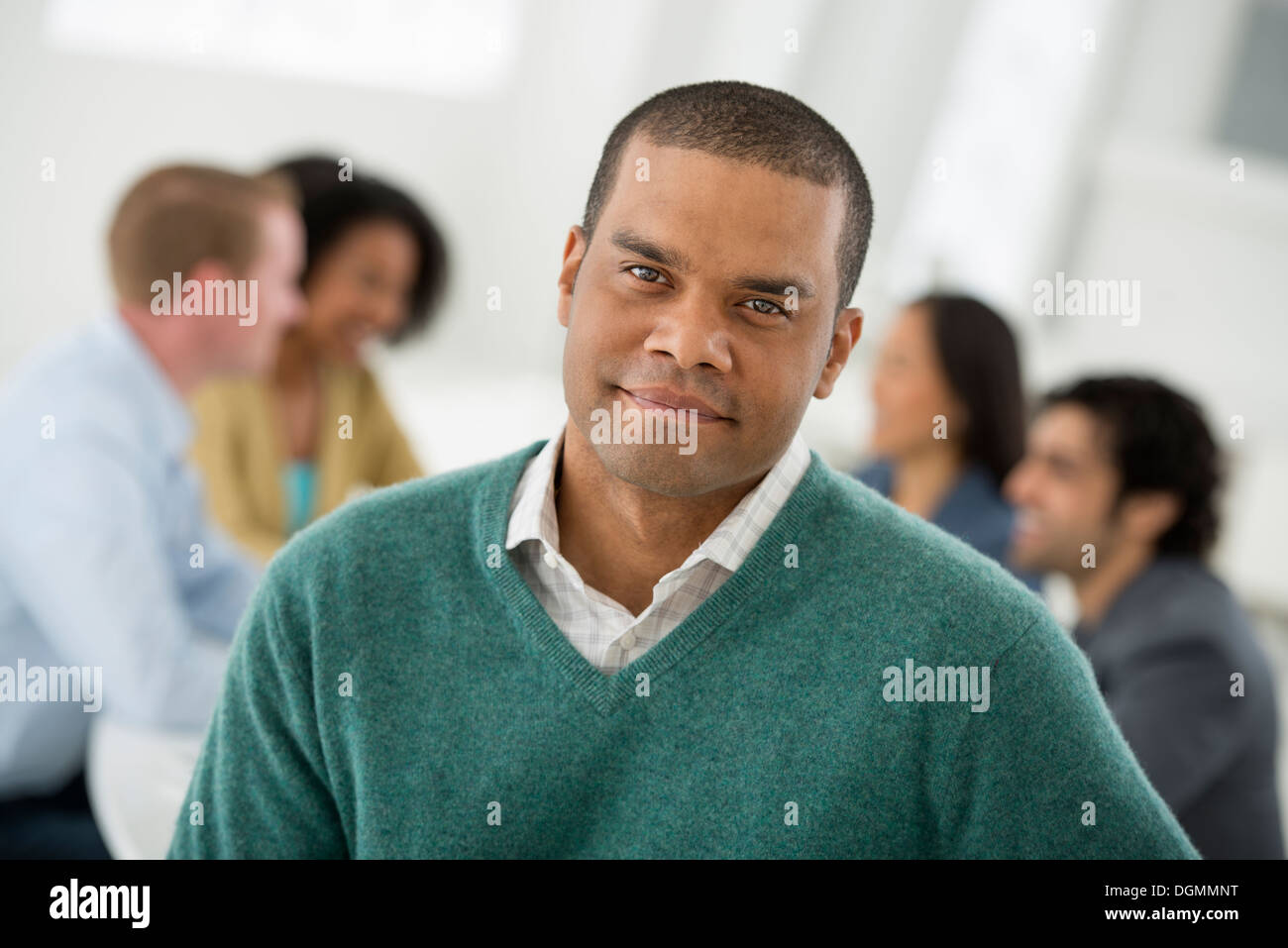 Business meeting. A group sitting down around a table. A man smiling confidently. Stock Photo