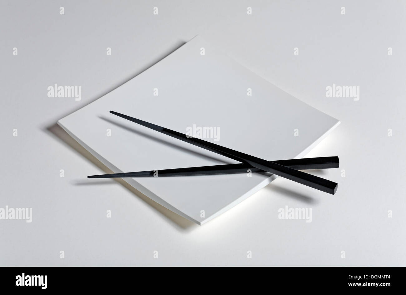 Black Japanese chopsticks on an empty white plate Stock Photo