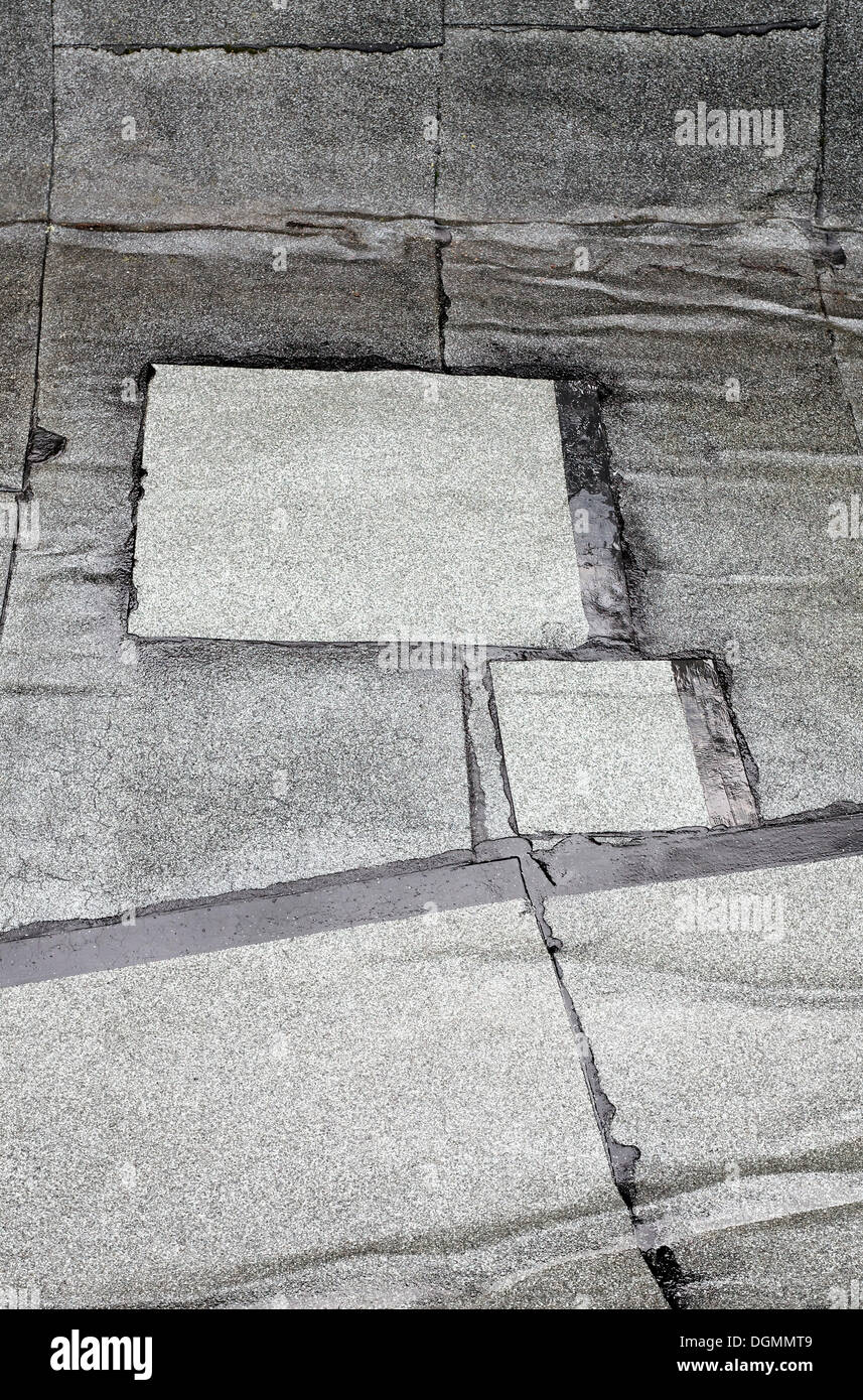 Patched-up, repaired areas on a roof made of roofing felt Stock Photo