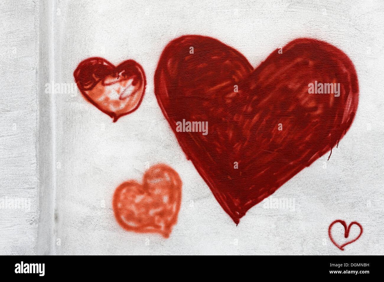 Different-sized red hearts painted on the wall of a house, graffiti Stock Photo