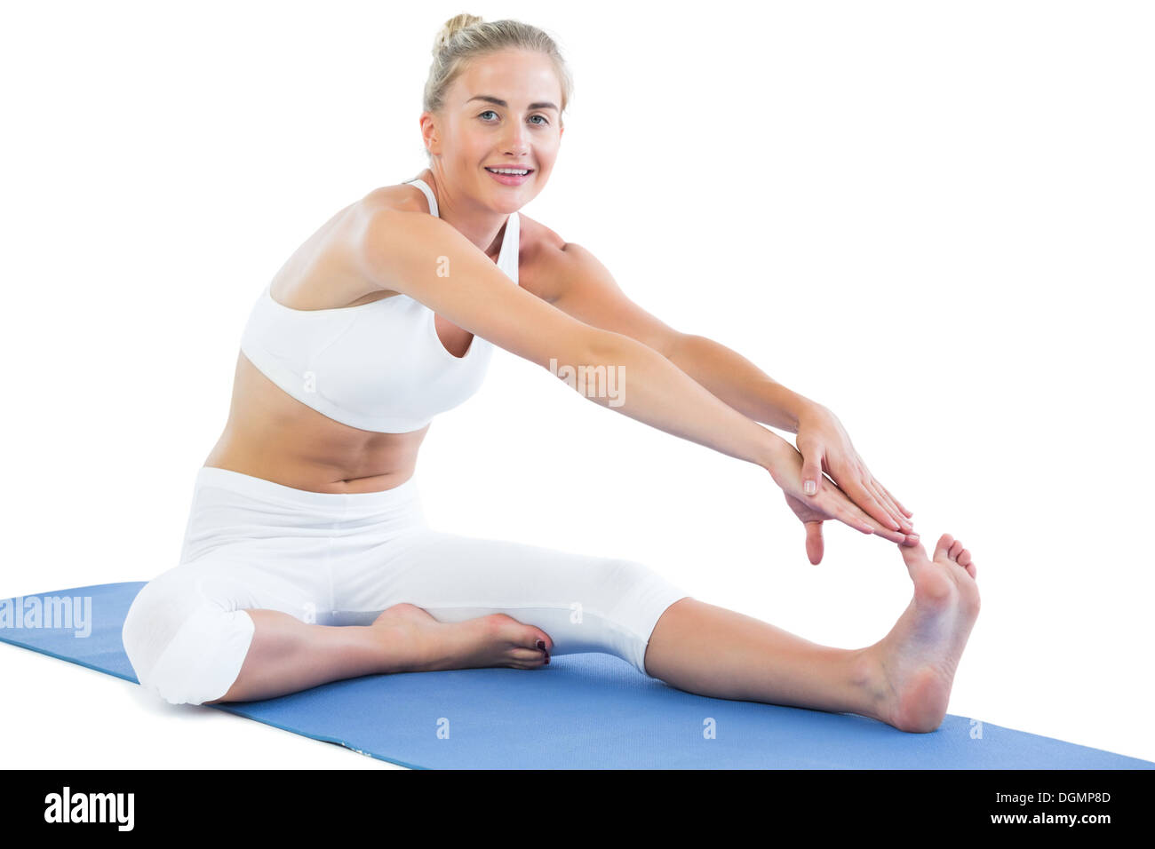 Toned smiling blonde sitting on exercise mat stretching right leg Stock Photo