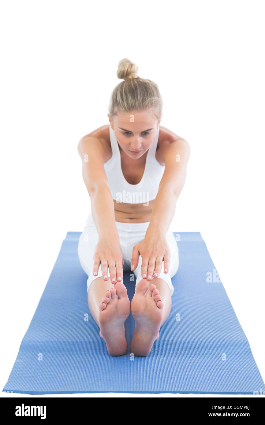Toned focused blonde sitting on exercise mat stretching legs Stock Photo