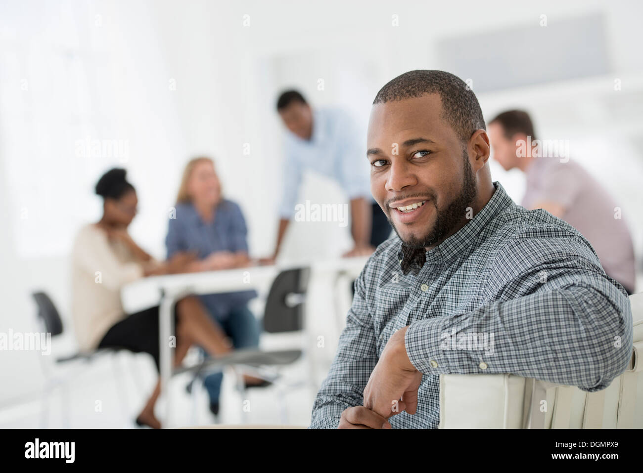 Office interior. Meeting. One person looking over her shoulder and away from the group. Stock Photo