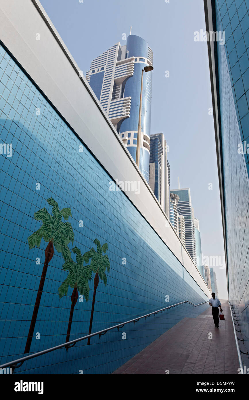 Single person walking through a pedestrian underpass with painted palm trees, Sheikh Zayed Road, Dubai, United Arab Emirates Stock Photo