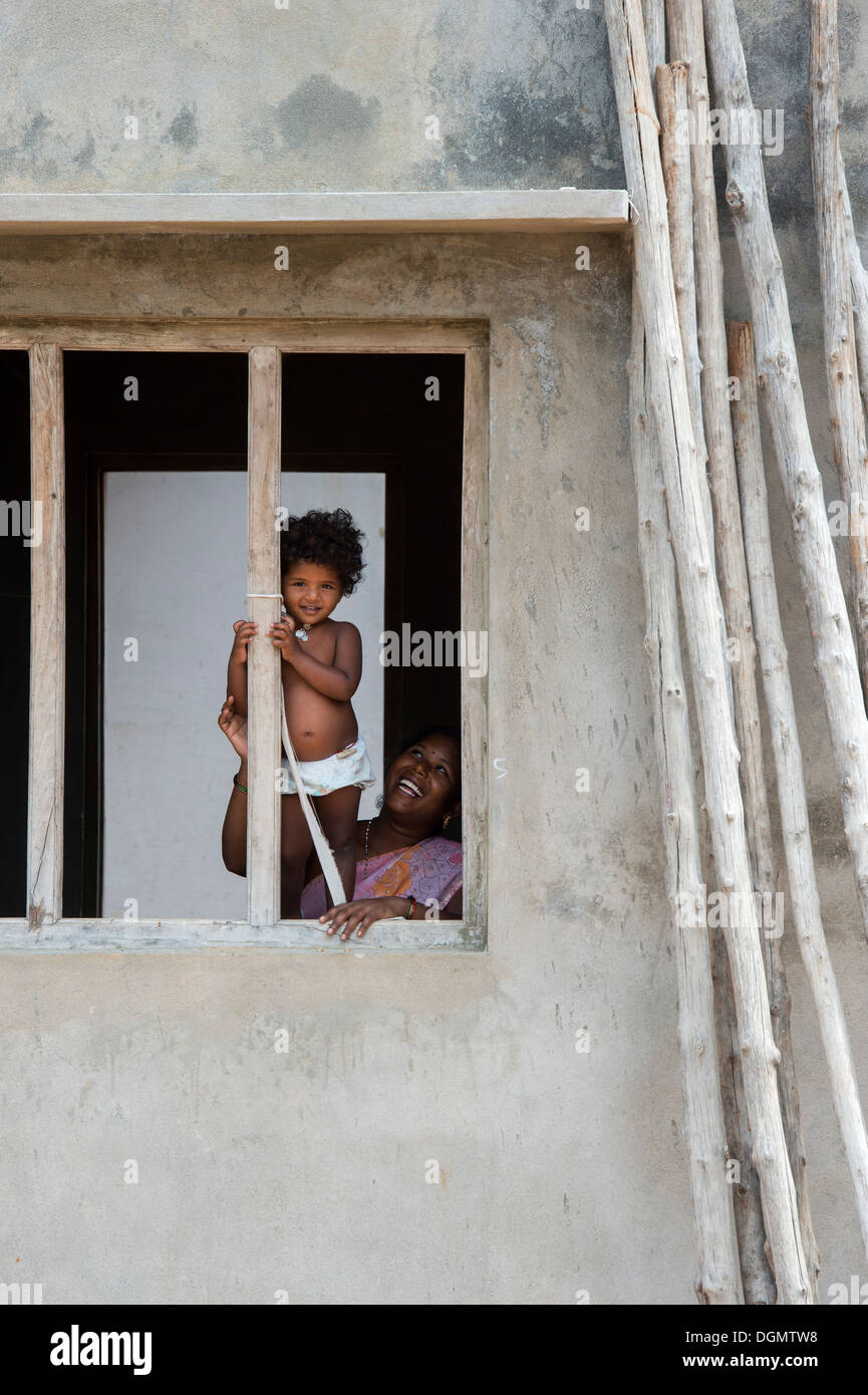 Young Indian baby girl standing in a window frame in a rural indian ...
