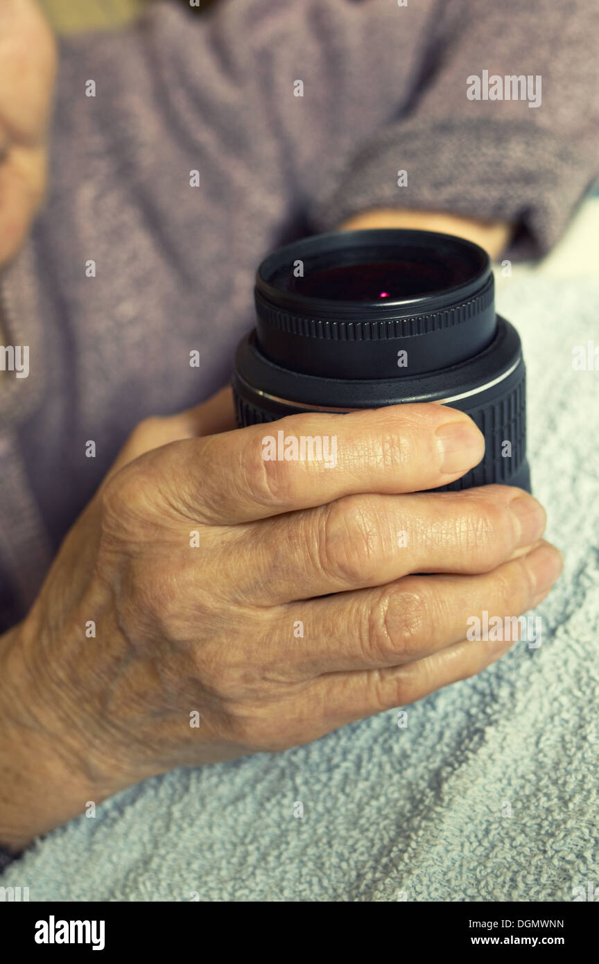 DSLR lens in old woman's hands. Stock Photo