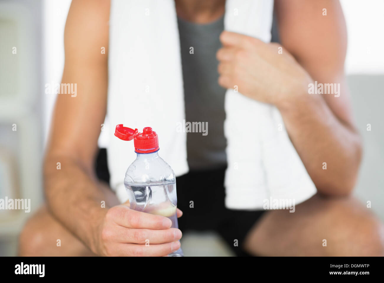 Close up of water bottle held by sporty man with towel Stock Photo