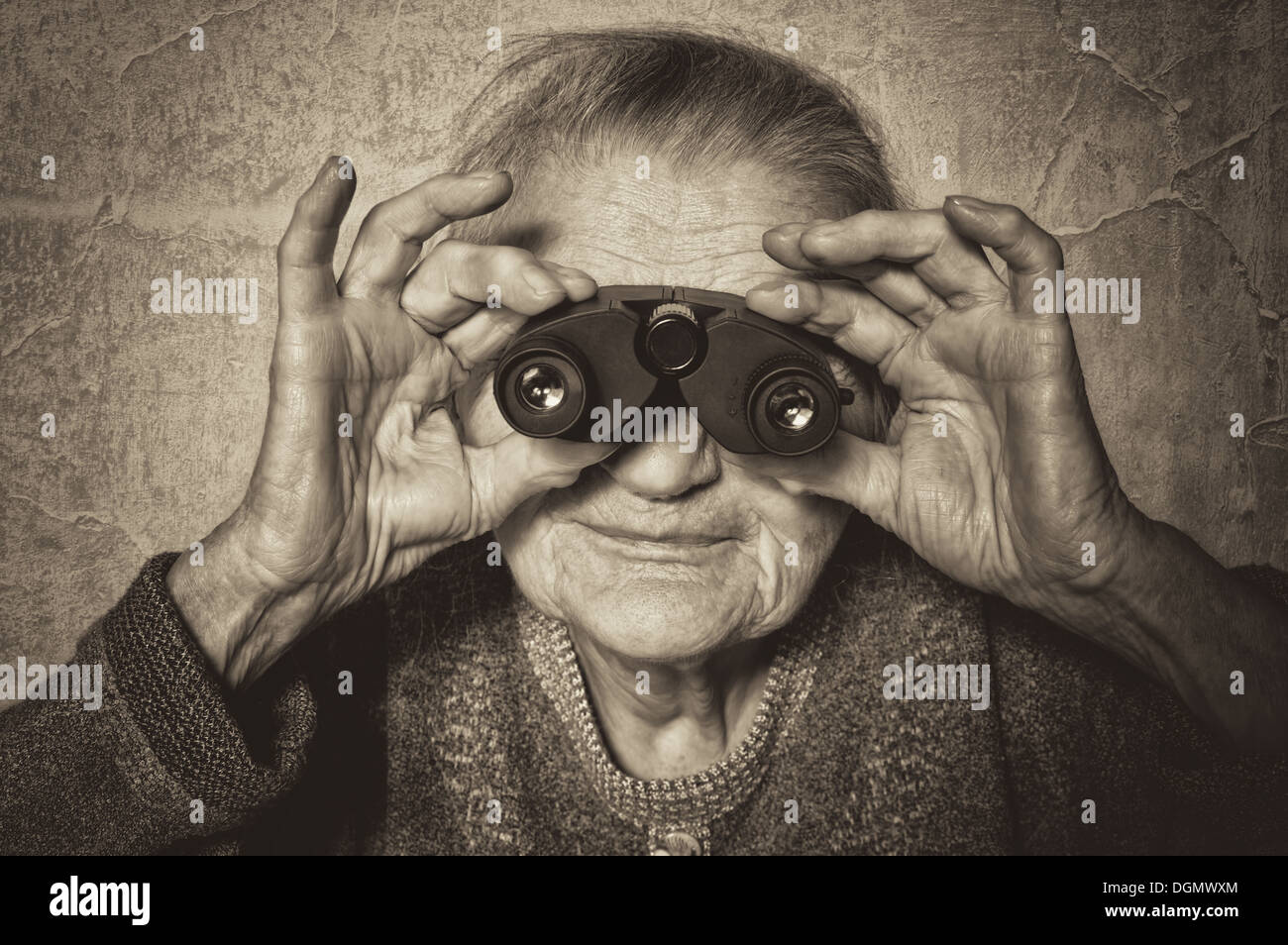 Vintage photo of elderly woman looks through binoculars. Stock Photo