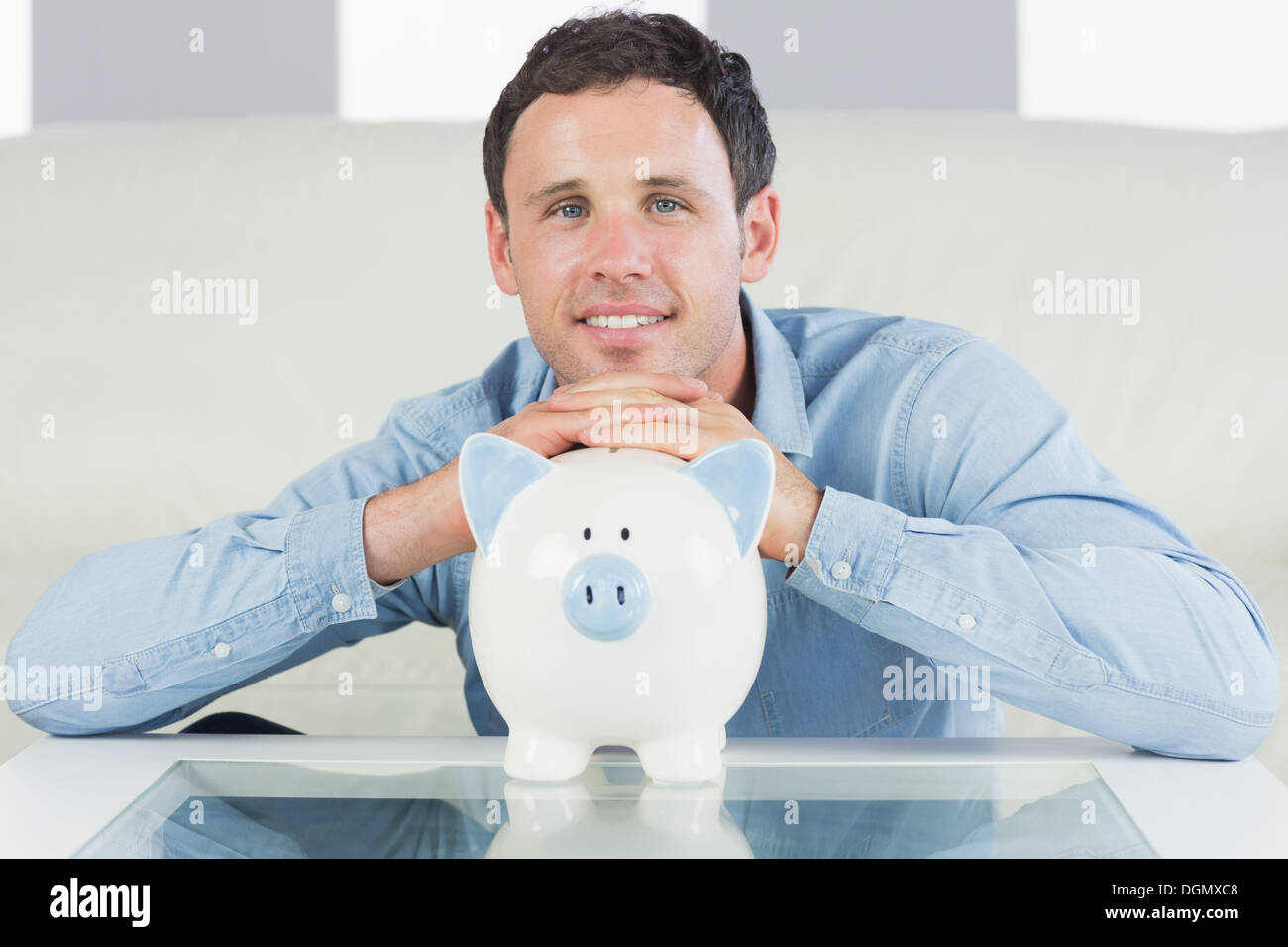 Cheerful casual man resting head on piggy bank Stock Photo