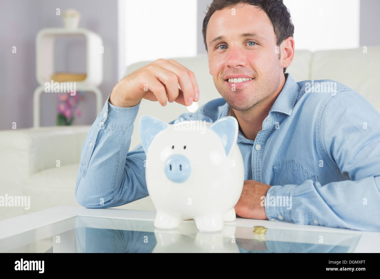 Handsome casual man putting coin in piggy bank smiling at camera Stock ...