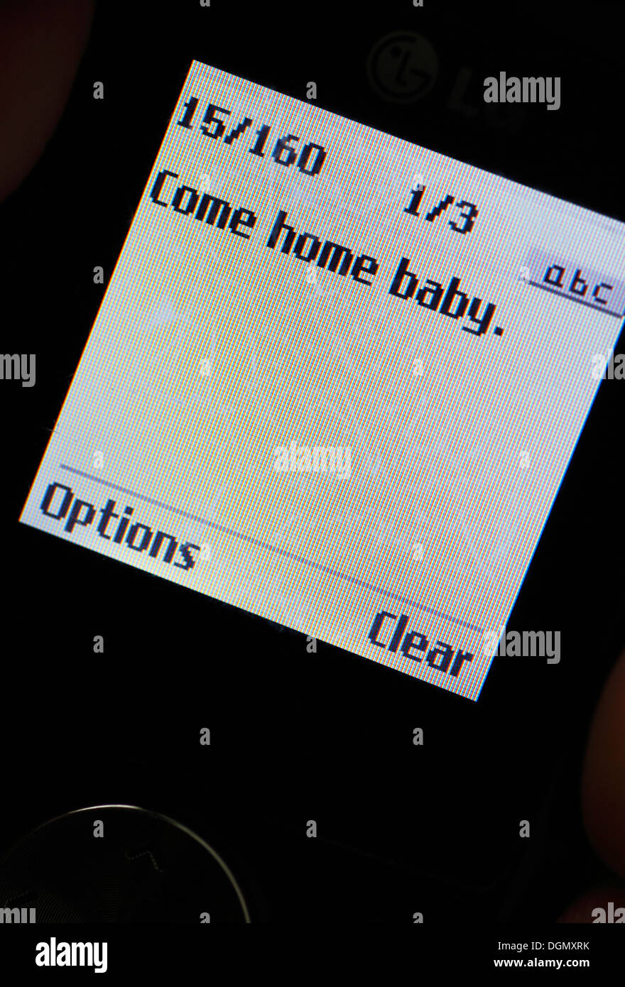 Mobile phone displaying the test message 'Come home baby'. Stock Photo