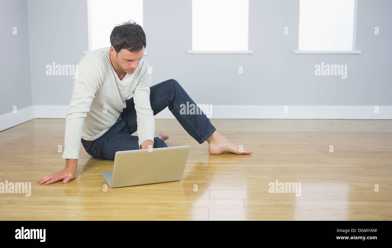 Casual handsome man sitting on floor using laptop Stock Photo - Alamy