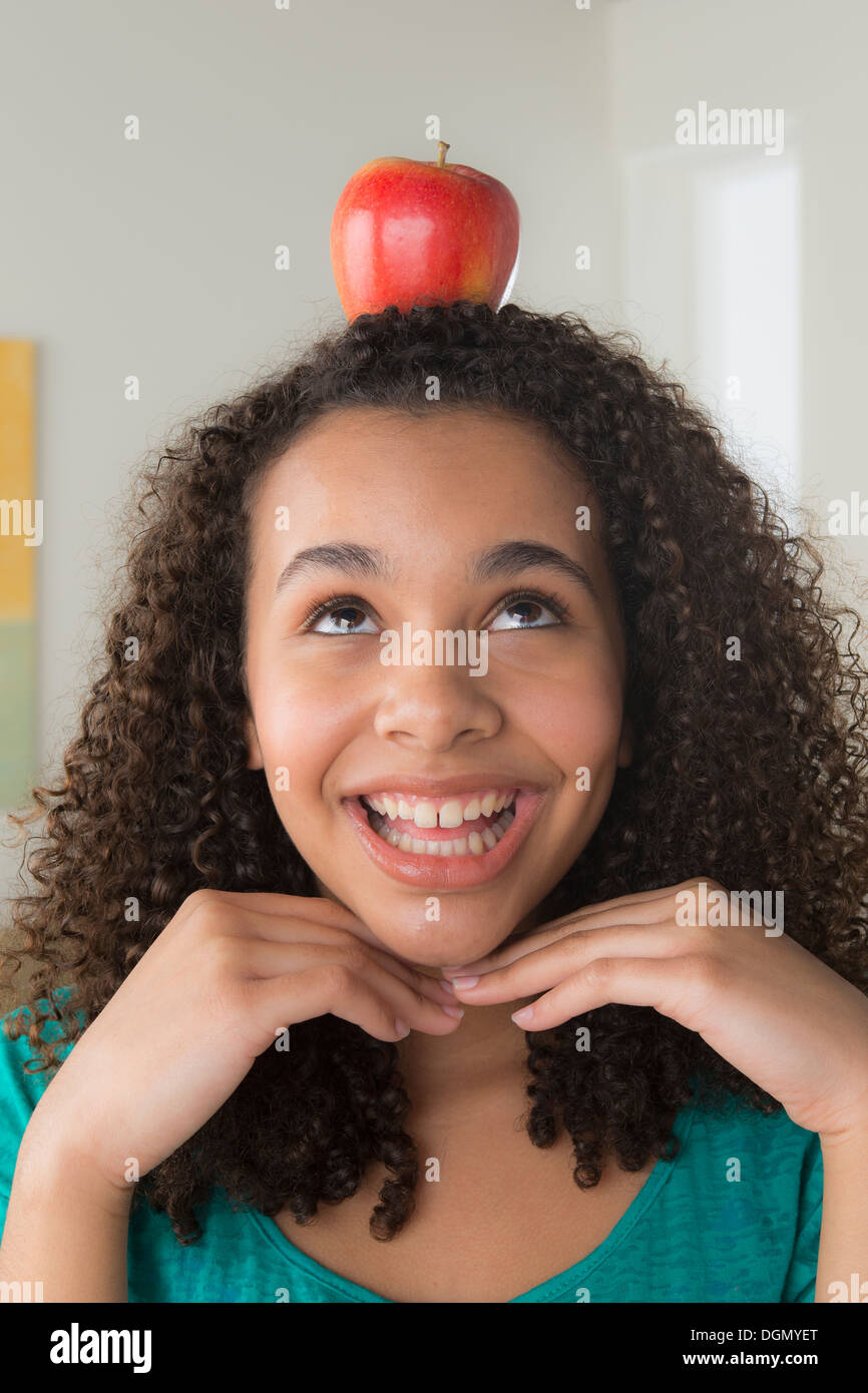Girl (-12-13) carrying apple on her head Stock Photo