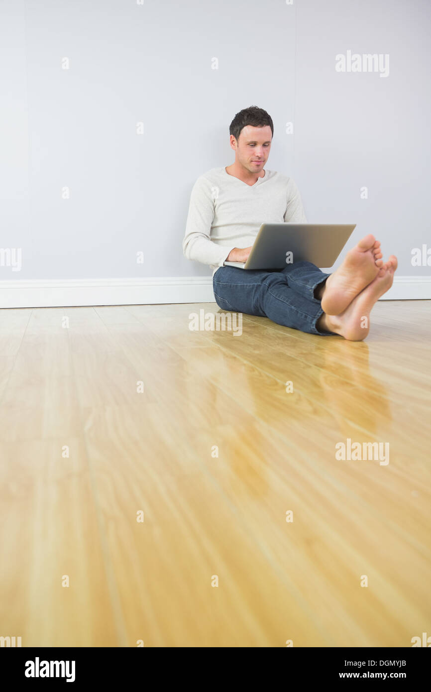 Casual attractive man leaning against wall using laptop Stock Photo