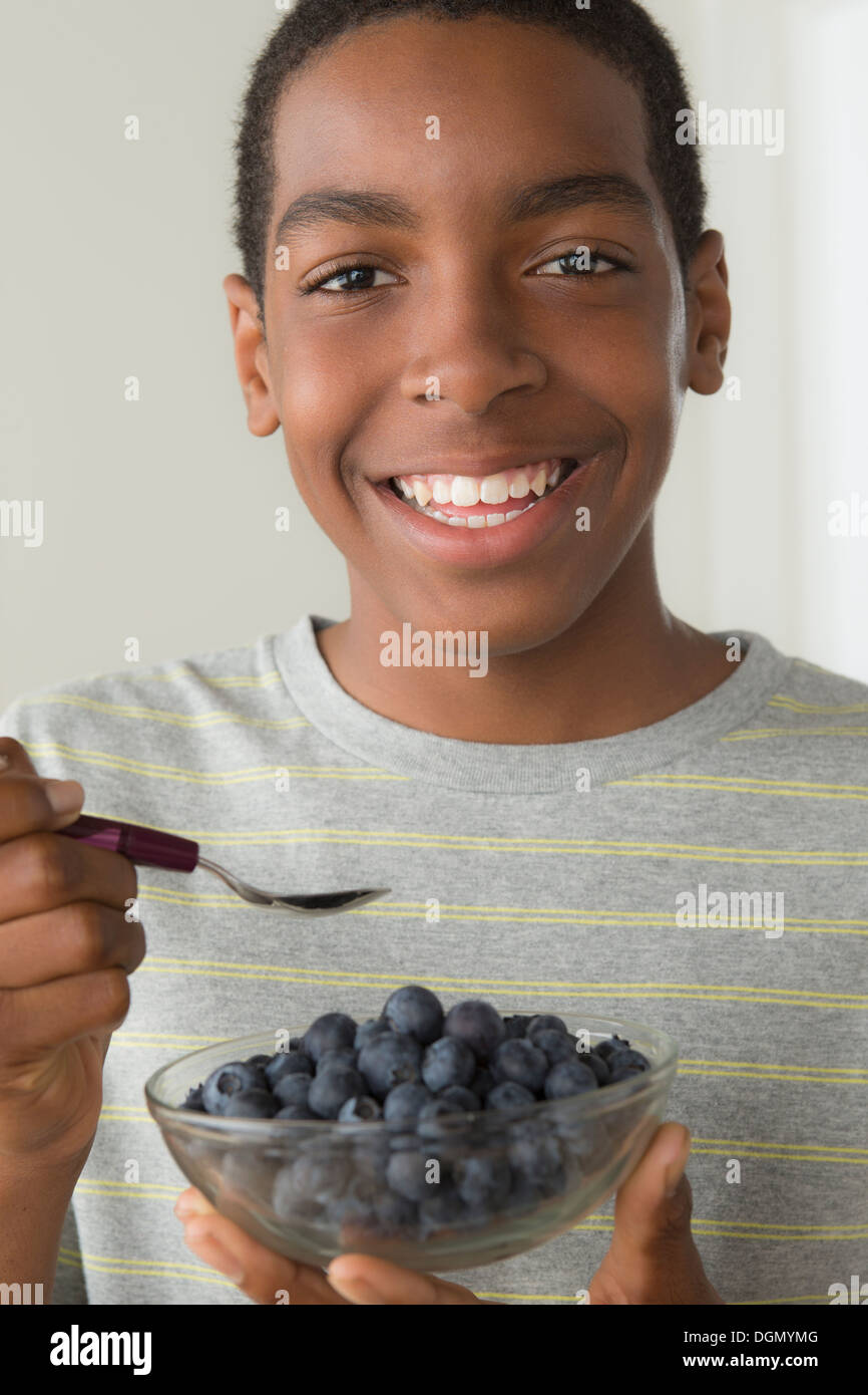 Boy (14-15) holding bowl of black berries Stock Photo
