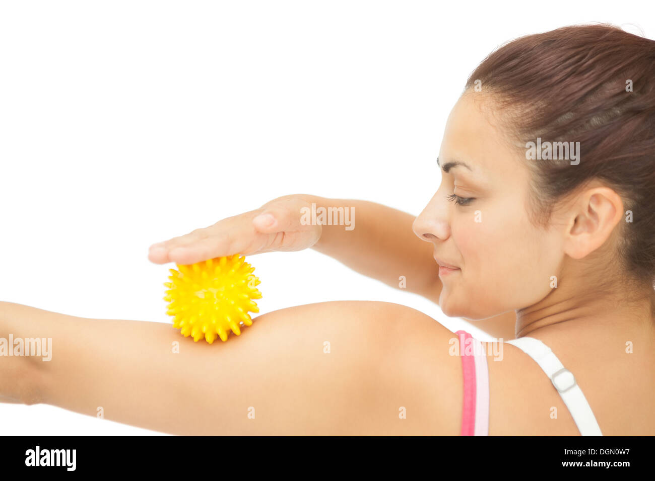 Calm sporty brunette touching arm with yellow massage ball Stock Photo