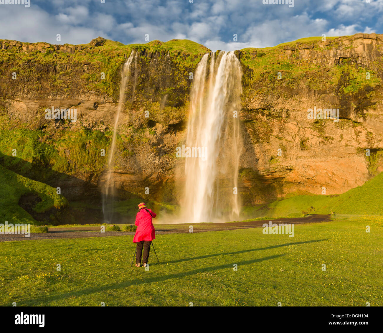Woman taking pictures of Seljalandsfoss Waterfall, Iceland Stock Photo
