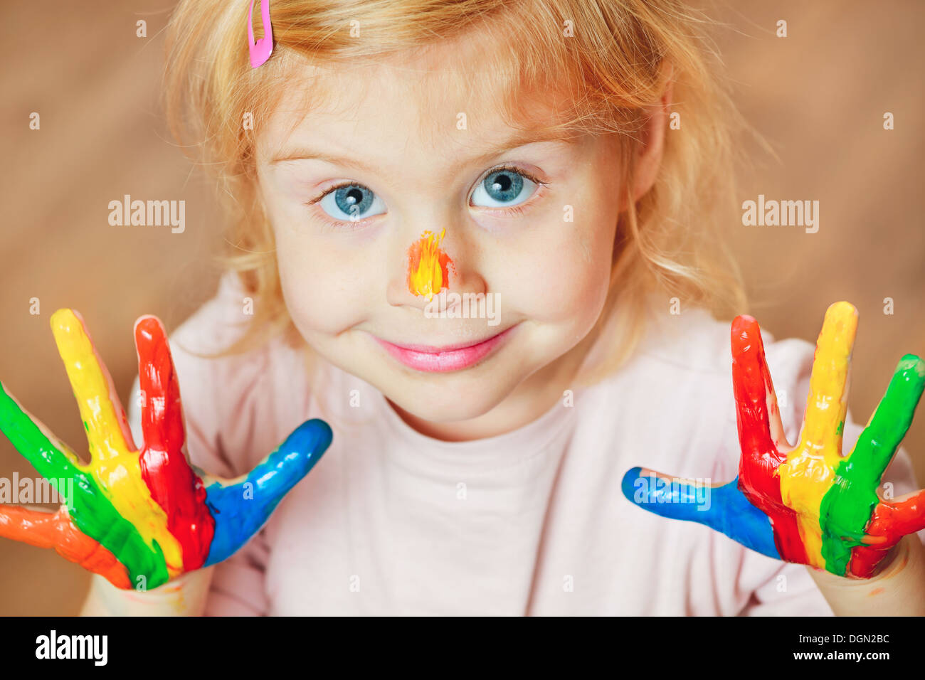 Cute little girl with painted hands looking at camera. Stock Photo