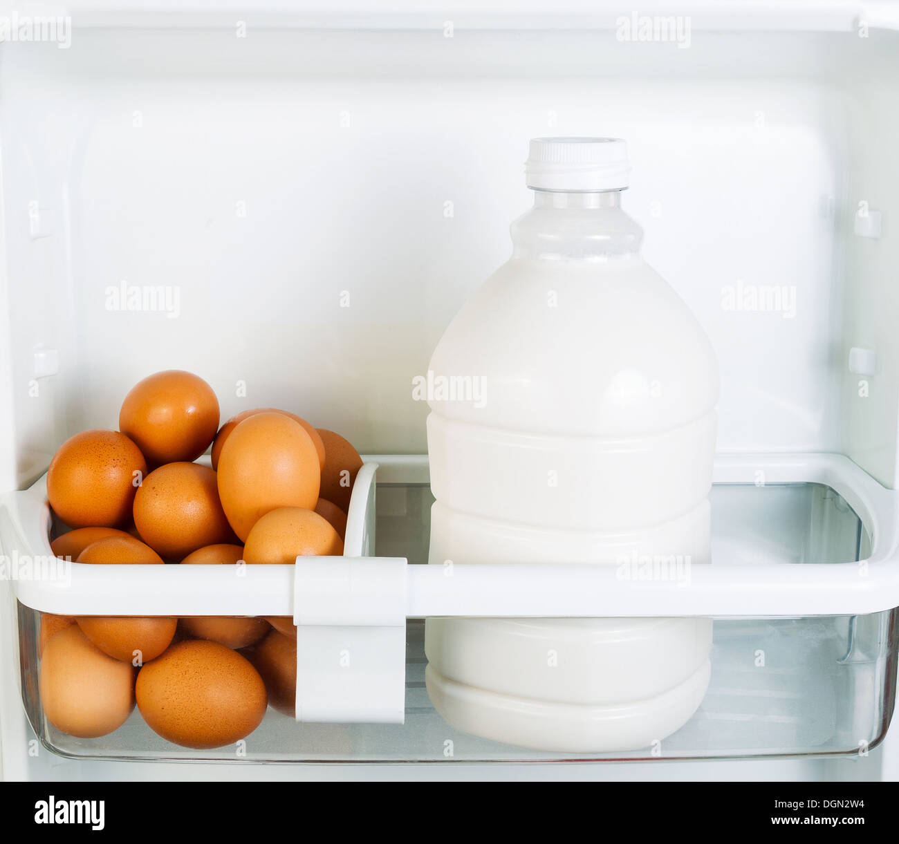 Photo of Fresh brown organic eggs and milk on inside of refrigerator door shelf Stock Photo