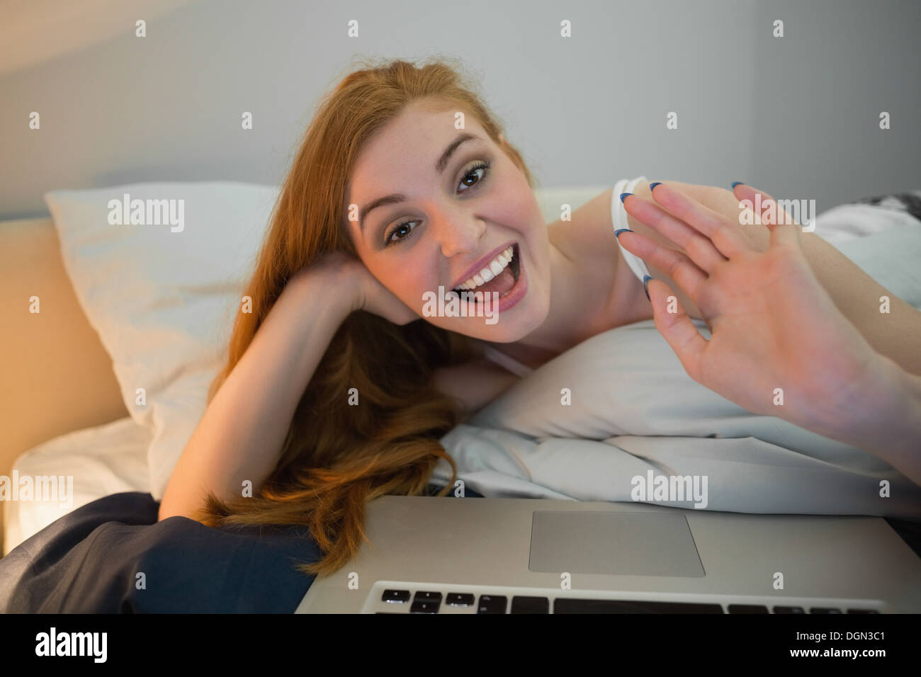 Pretty redhead waving to laptop on video chat Stock Photo