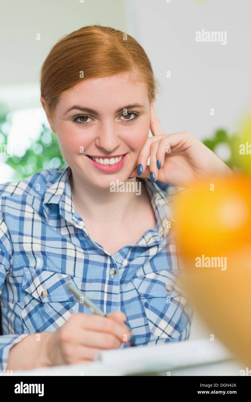 Cheerful redhead writing at her desk Stock Photo