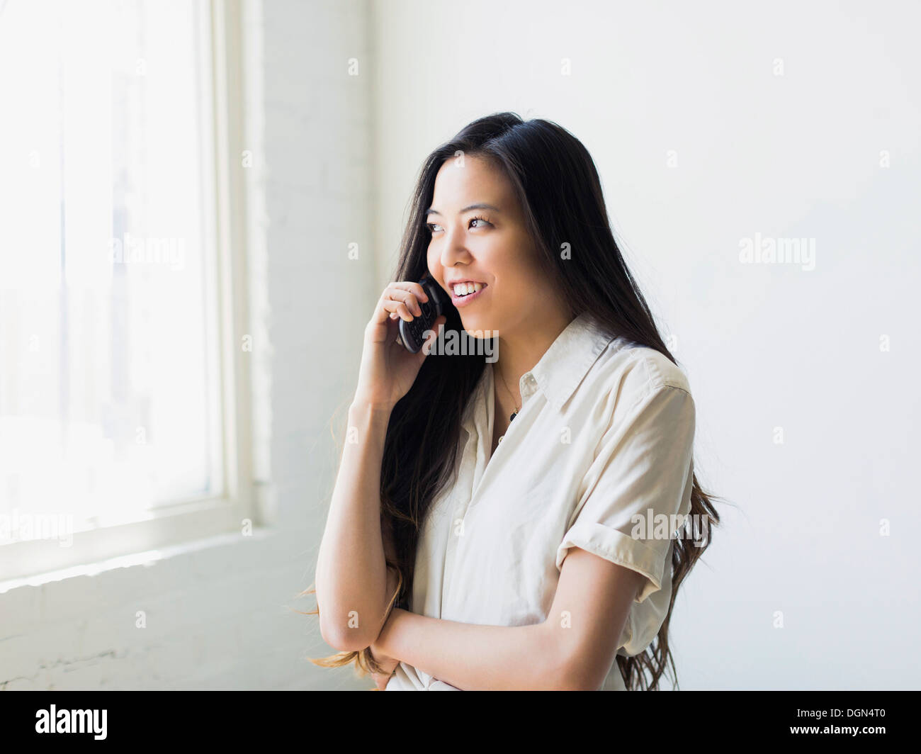 Smiling young woman talking via mobile phone Stock Photo