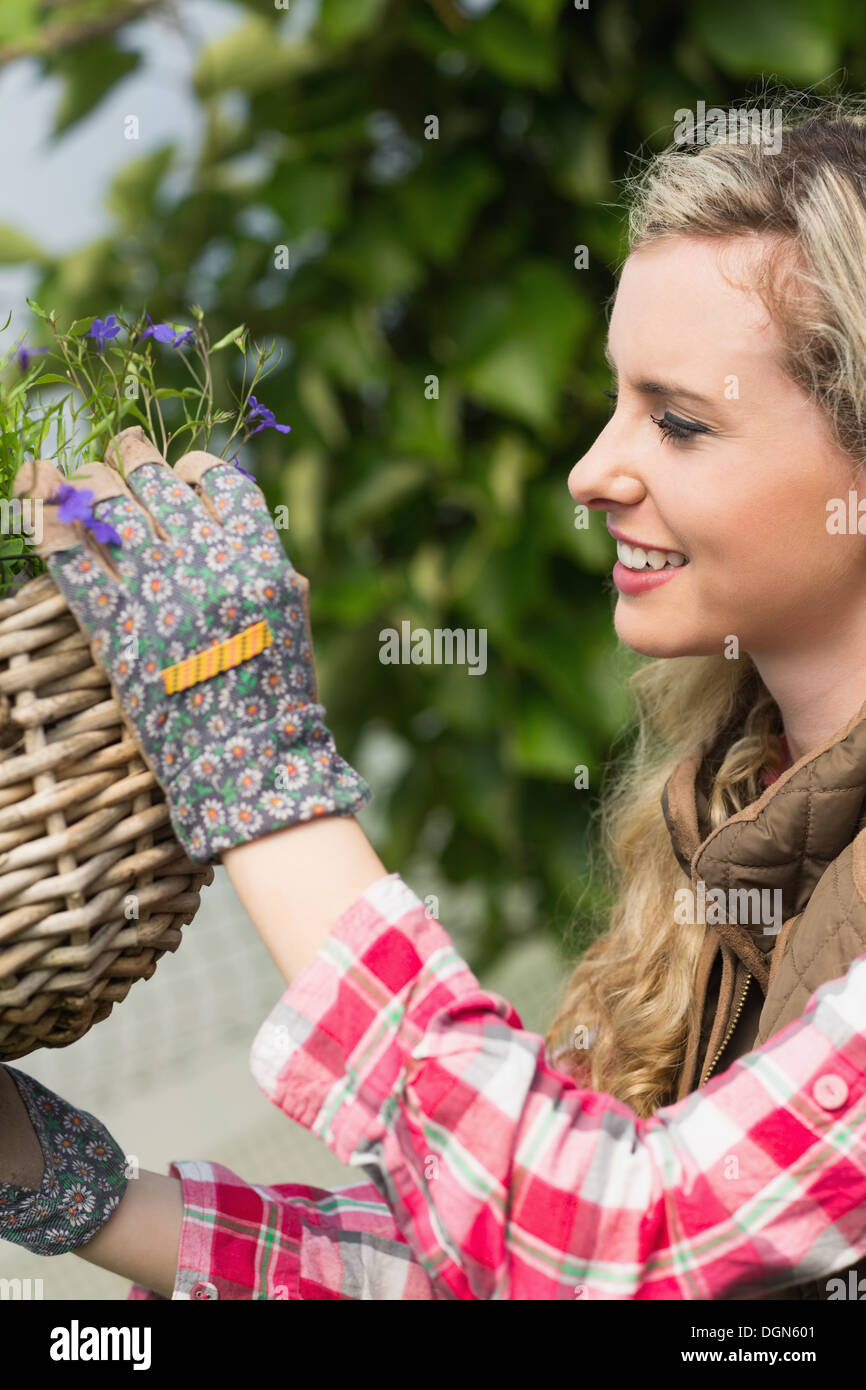 Pretty blonde fixing a hanging flower basket Stock Photo