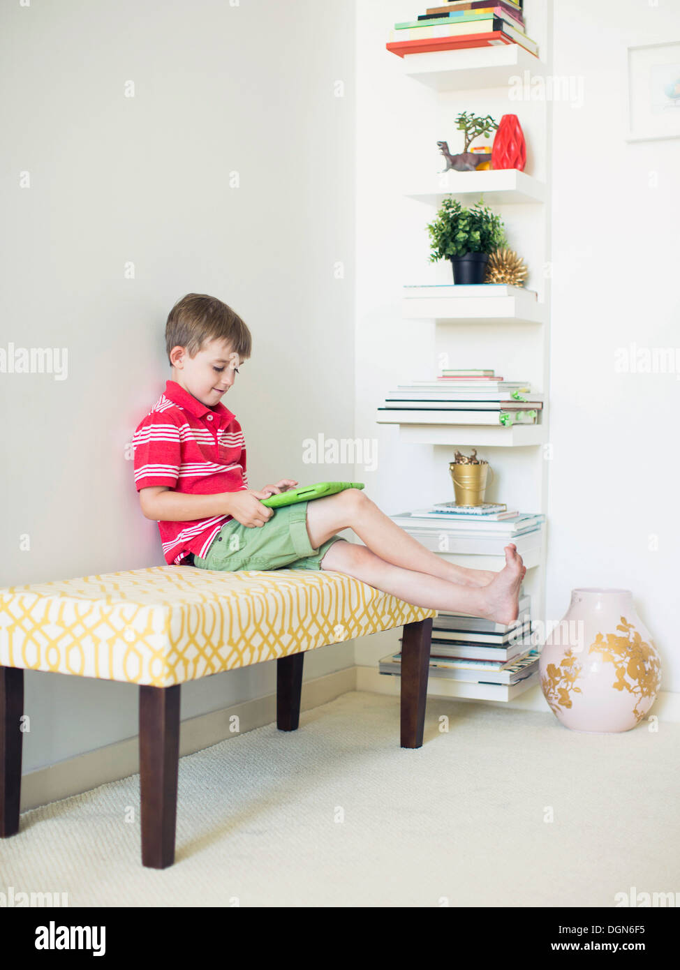 Boy (6-7) sitting on bench using digital tablet Stock Photo
