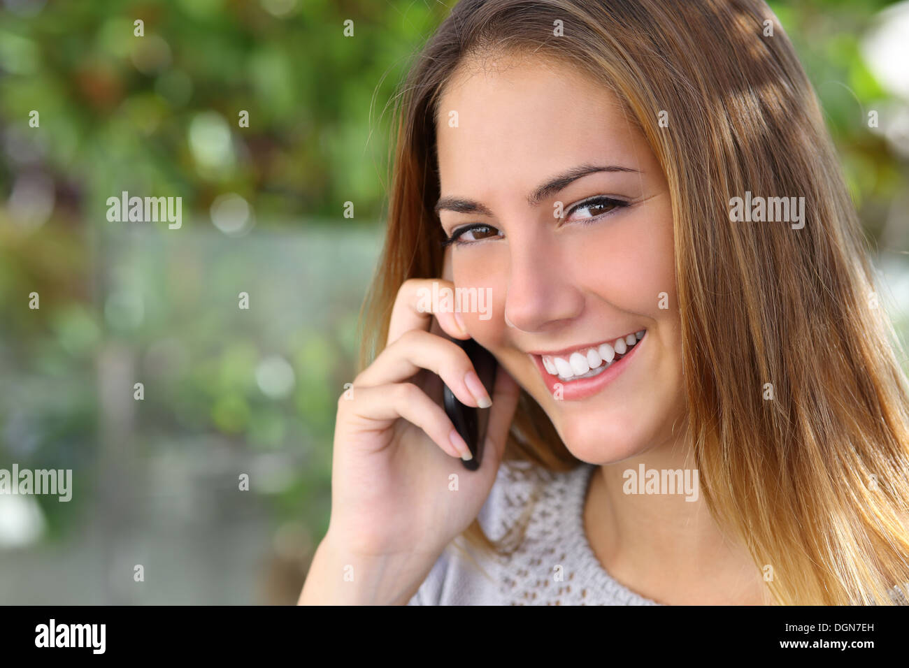 Portrait of a beautiful woman with a perfect white smile talking on the mobile phone outdoor Stock Photo