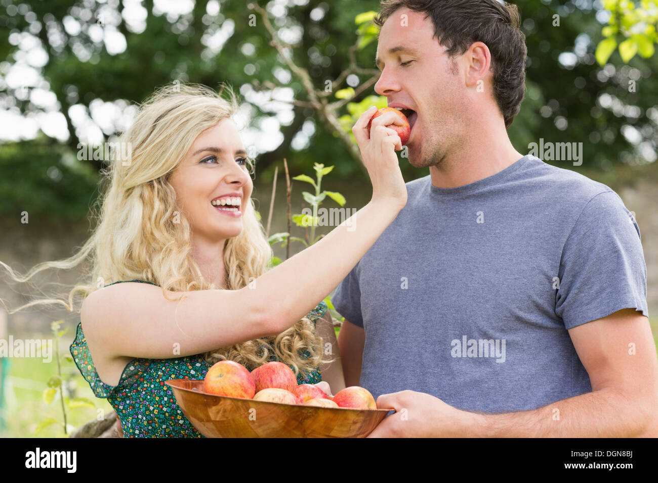 Blonde woman feeding her boyfriend with an apple Stock Photo