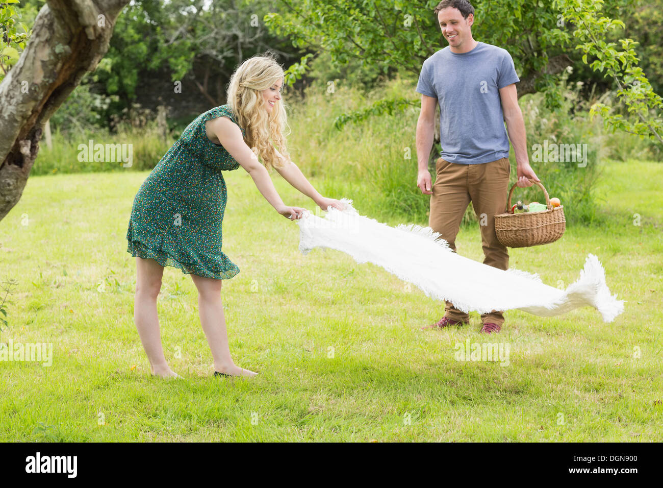 Blonde woman spreading a blanket for a picnic with her boyfriend Stock Photo