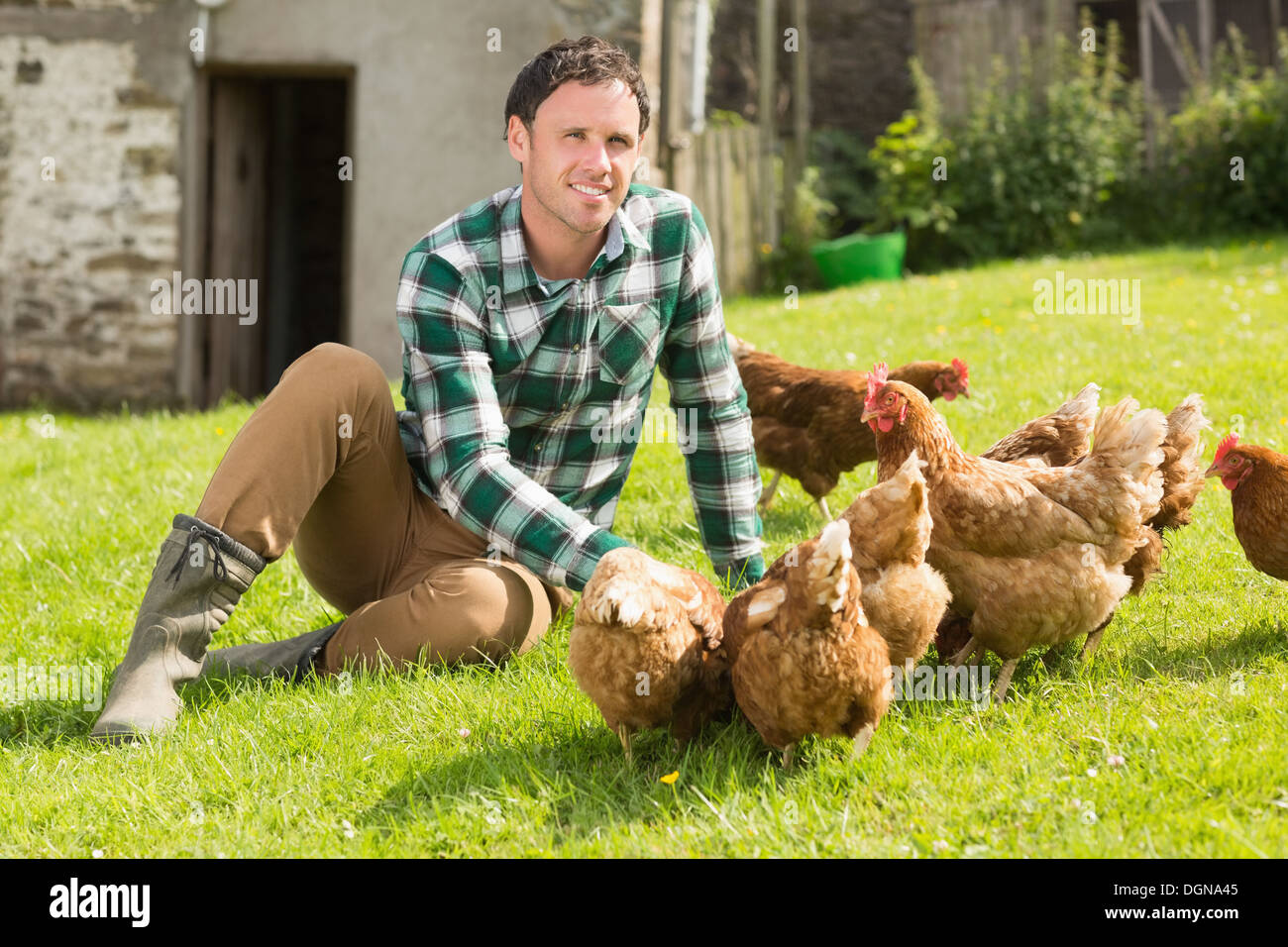 Young man feeding his chickens smiling at camera Stock Photo