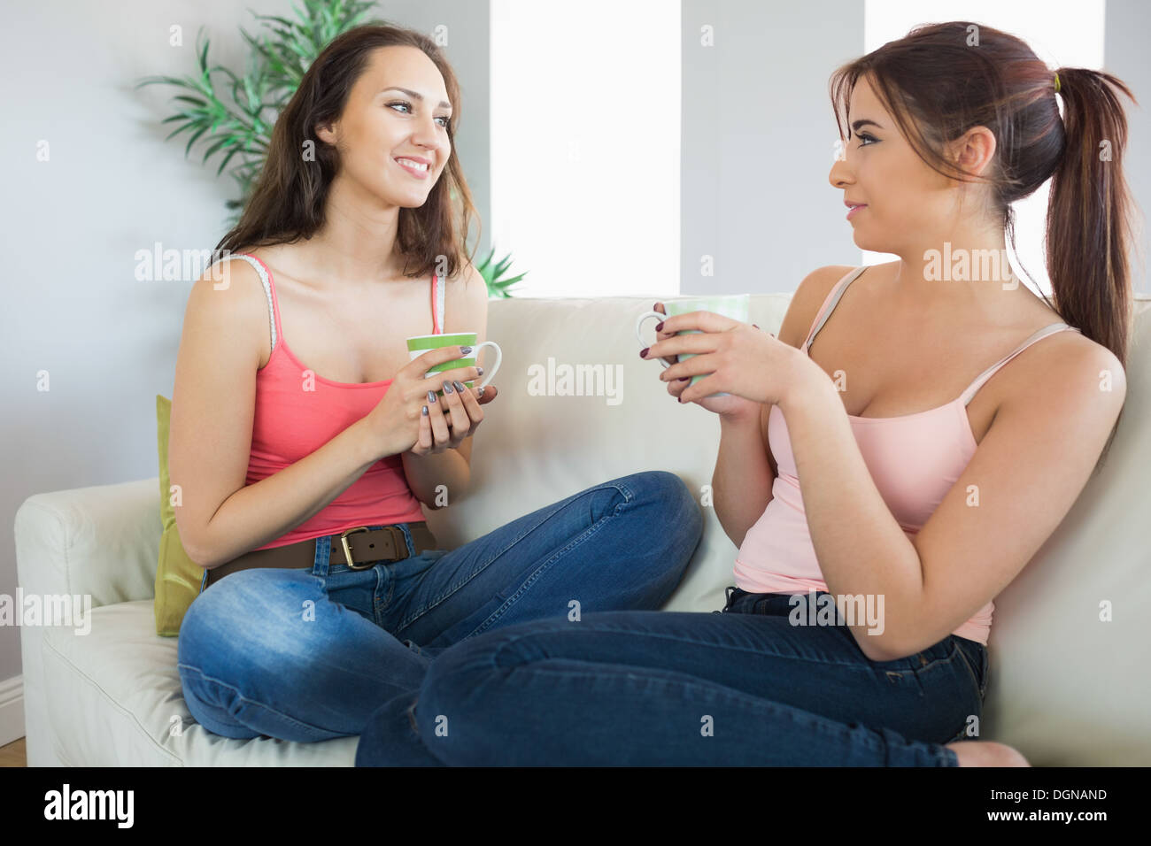 https://c8.alamy.com/comp/DGNAND/cute-young-women-holding-cups-sitting-on-a-couch-DGNAND.jpg
