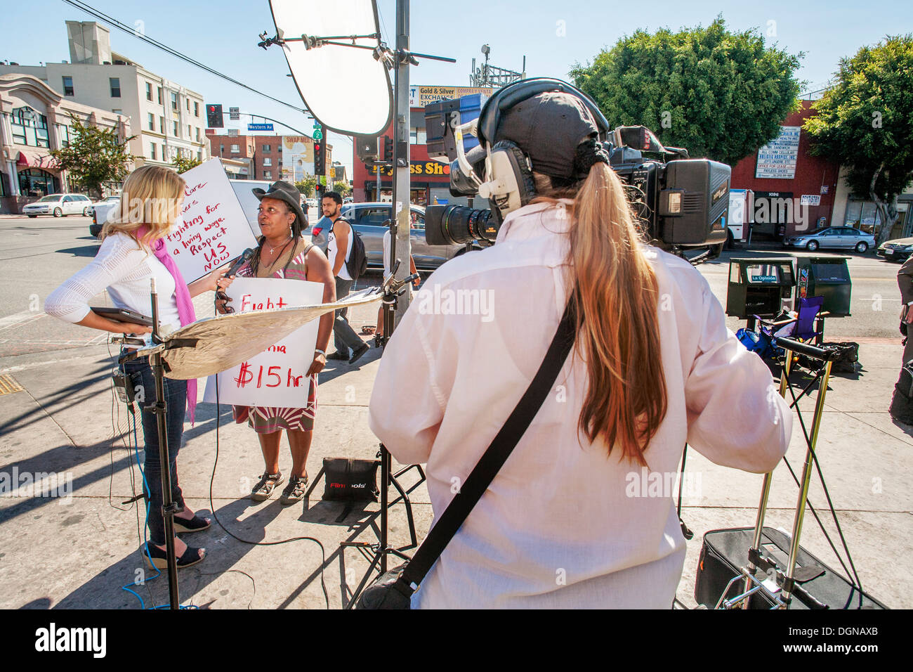 A television broadcast journalist interviews an African American woman participant in a demonstration of fast food workers in LA Stock Photo
