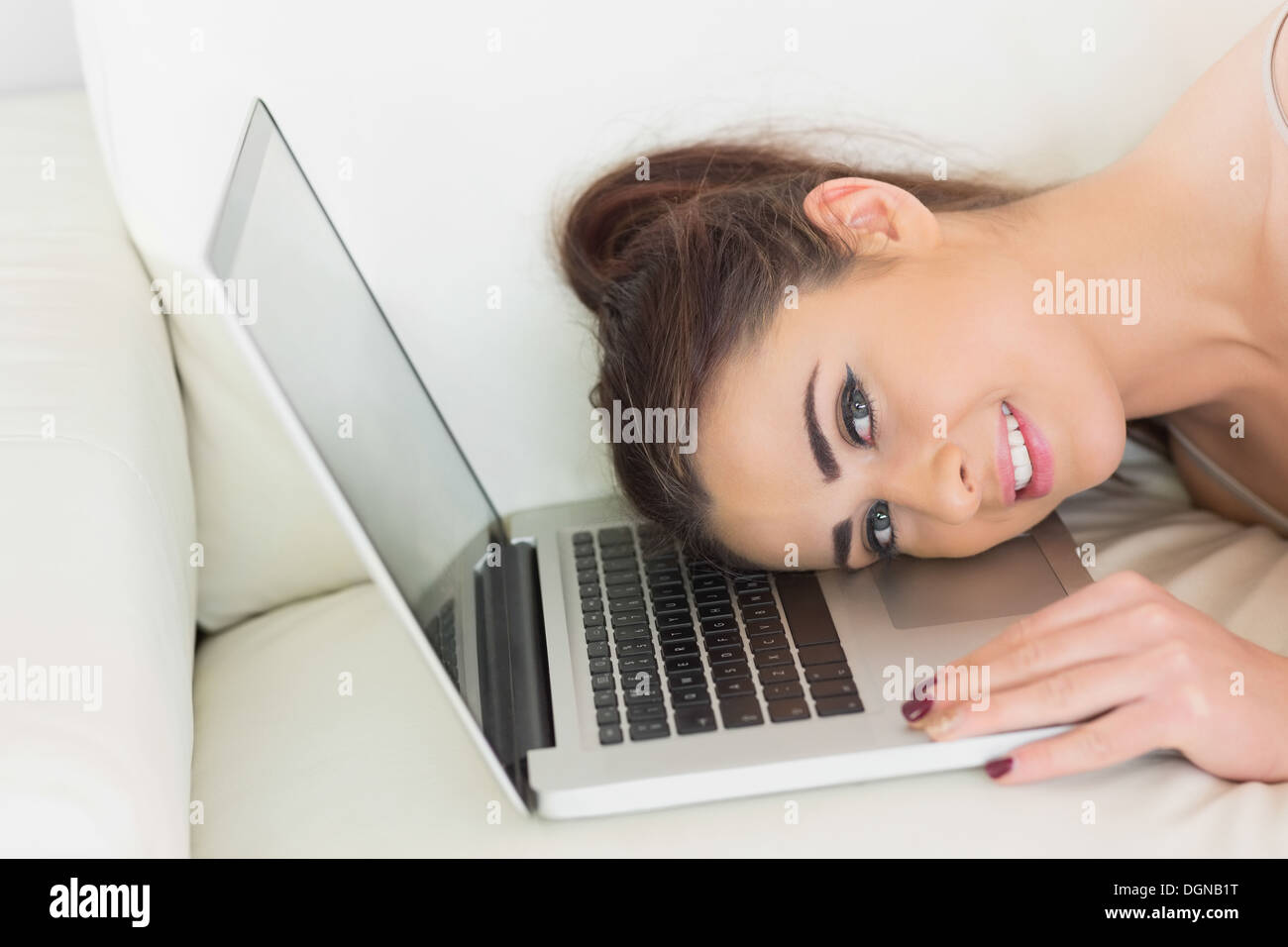 Pretty glad woman lying with her head on a laptop Stock Photo