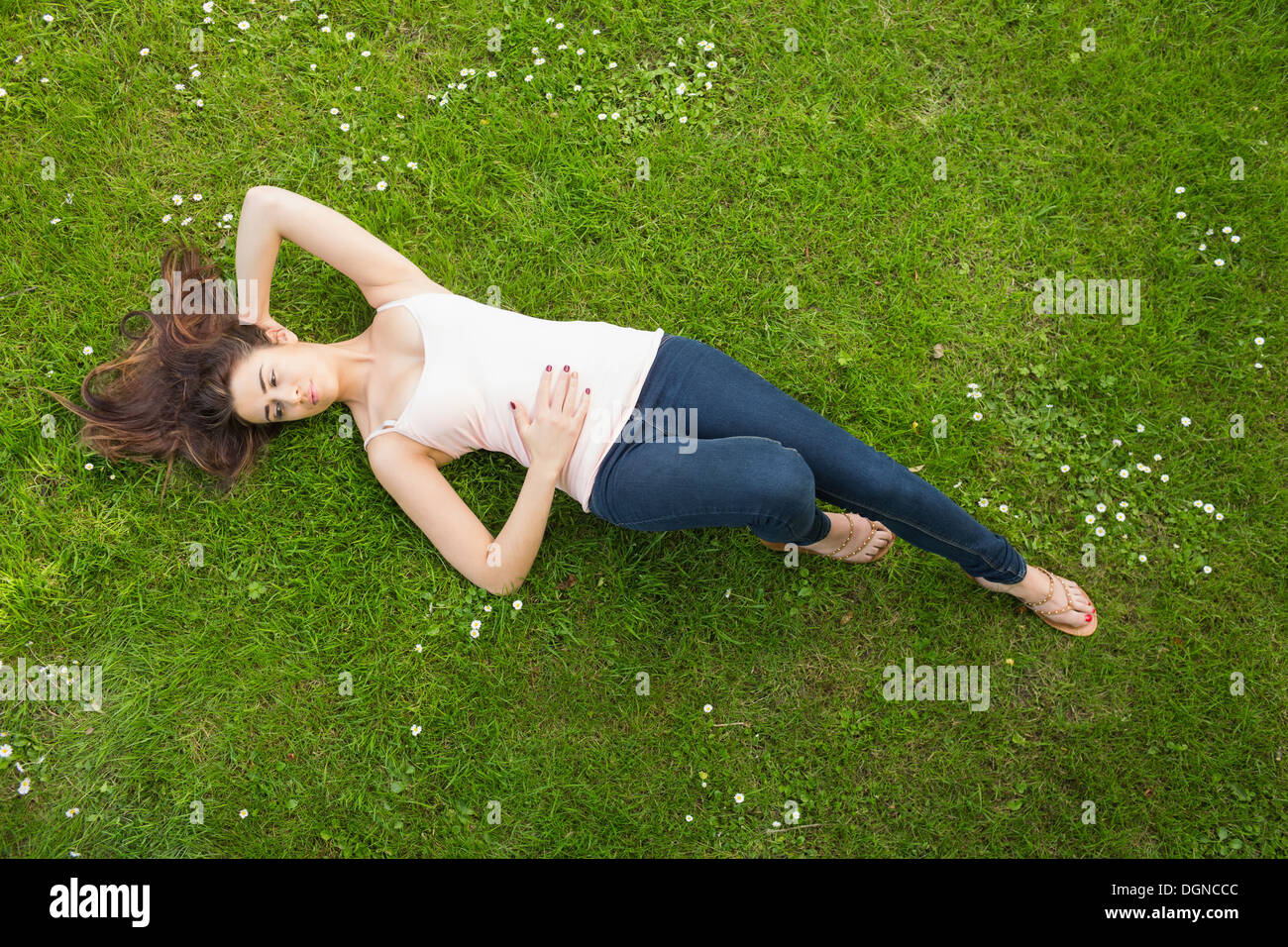 Beautiful brunette woman lying on grass Stock Photo