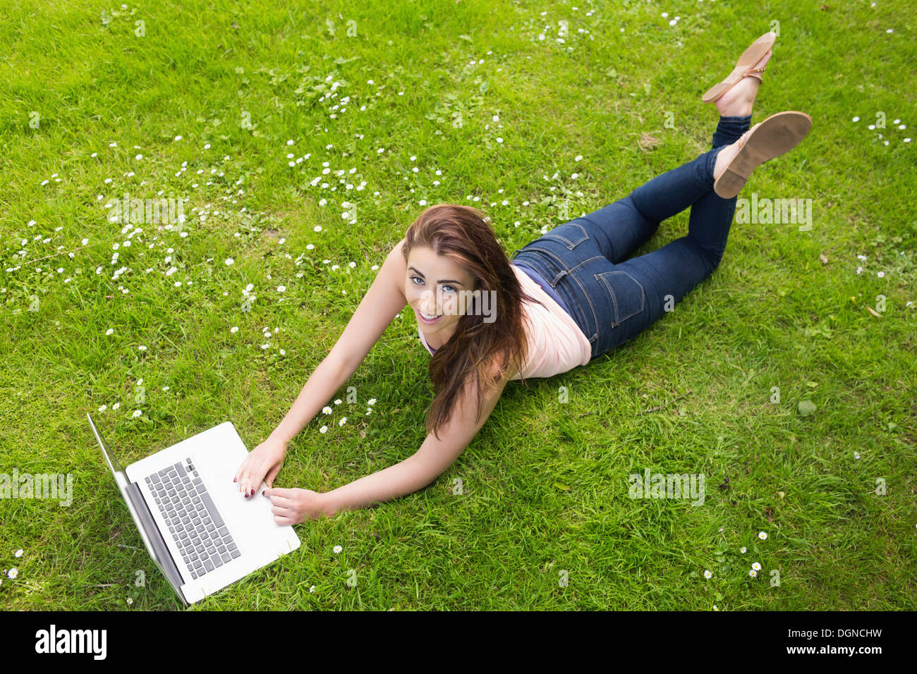 Happy young woman lying on a lawn using her laptop Stock Photo - Alamy
