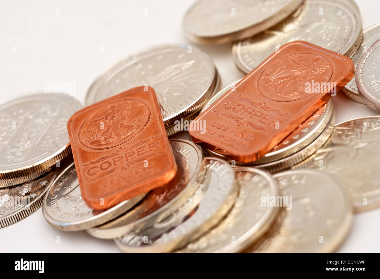 A stack of silver bullion coins with two copper bars on top Stock Photo