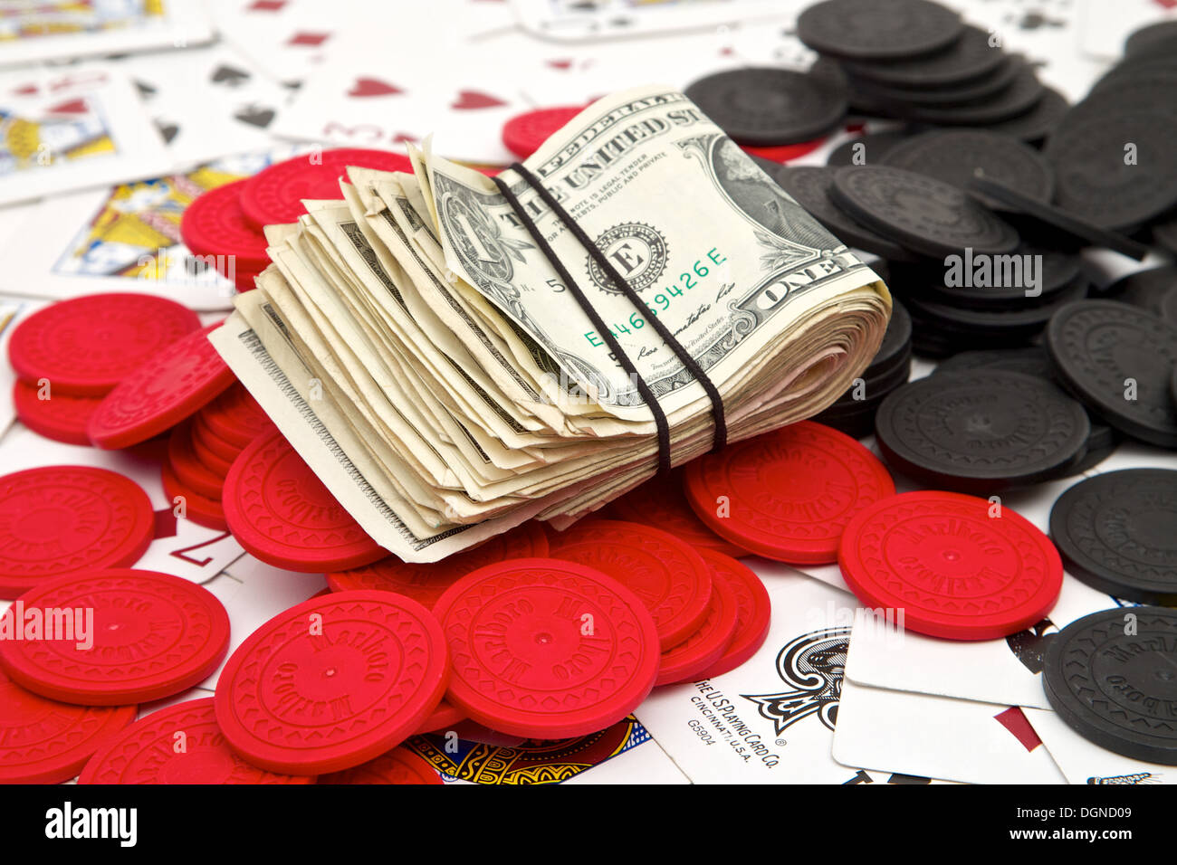 A stack of money and poker chips on a pile of playing cards Stock Photo