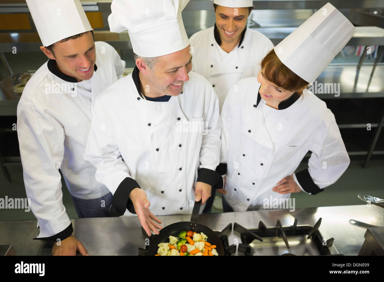 Experienced head chef showing pan to his colleagues Stock Photo