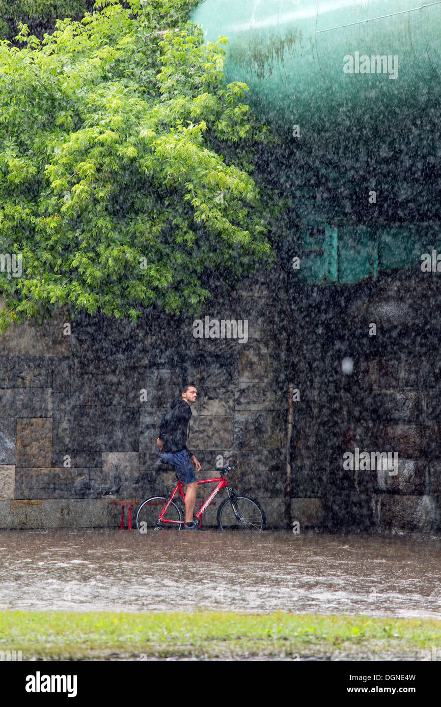 Warsaw, Poland, a bike rider waits for the end of a heavy downpour Stock Photo