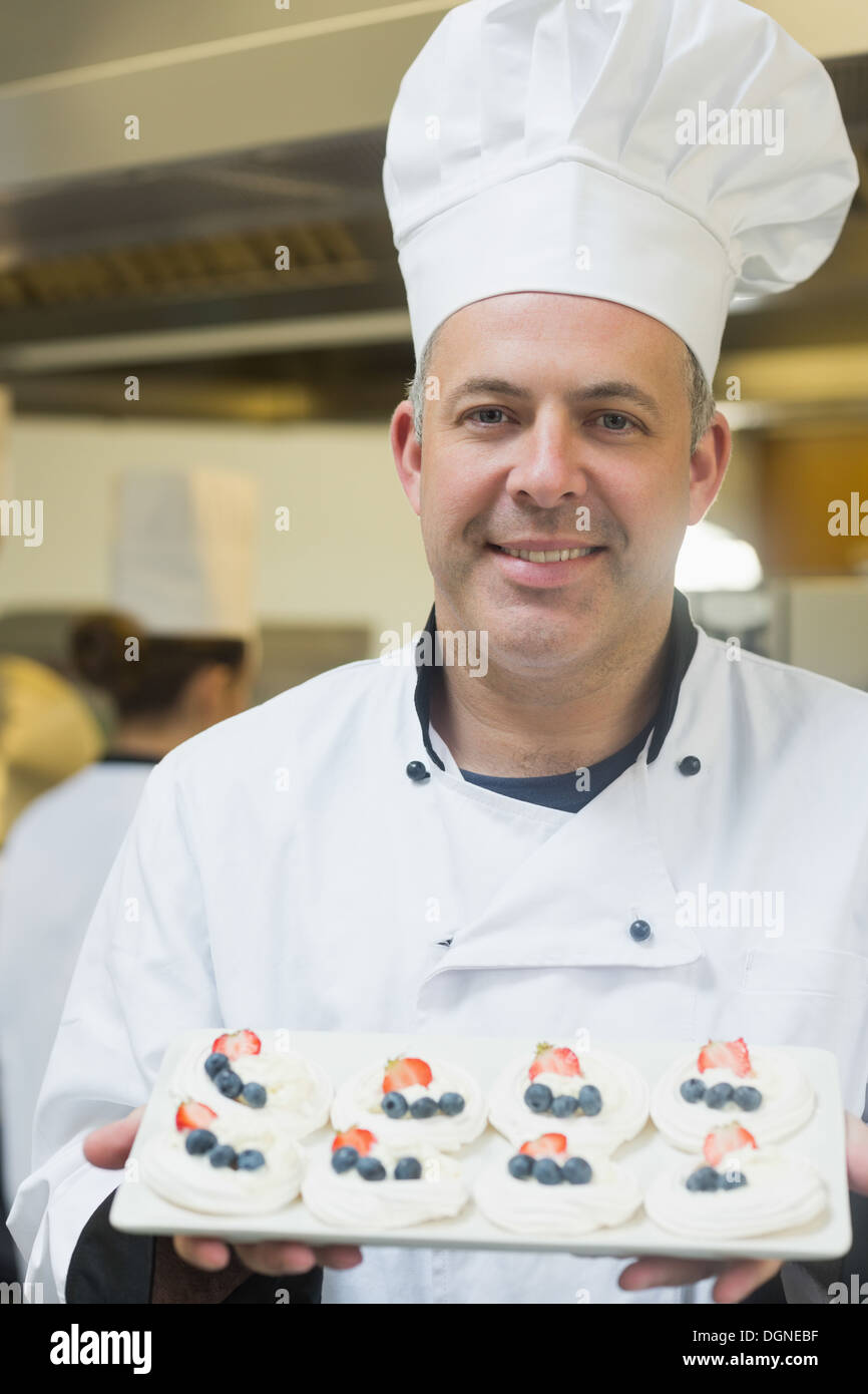 Happy chef presenting plate of meringues Stock Photo
