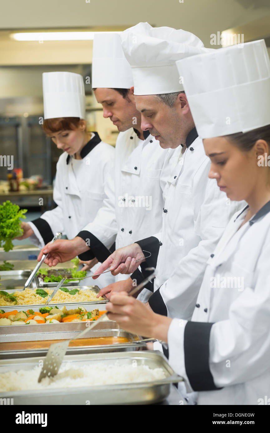 Four chefs working at serving trays Stock Photo