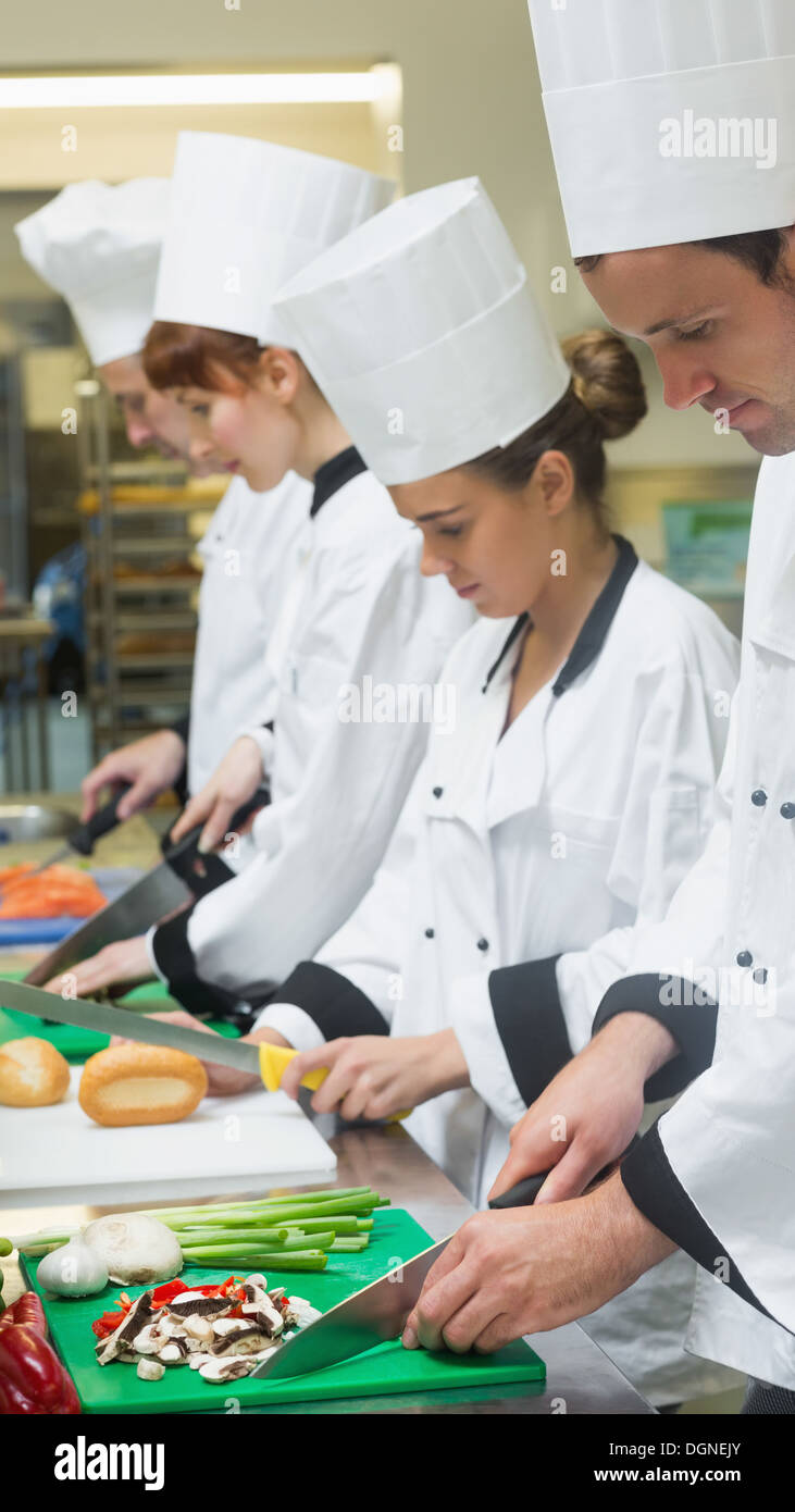 Chefs standing in a row cutting vegetables Stock Photo