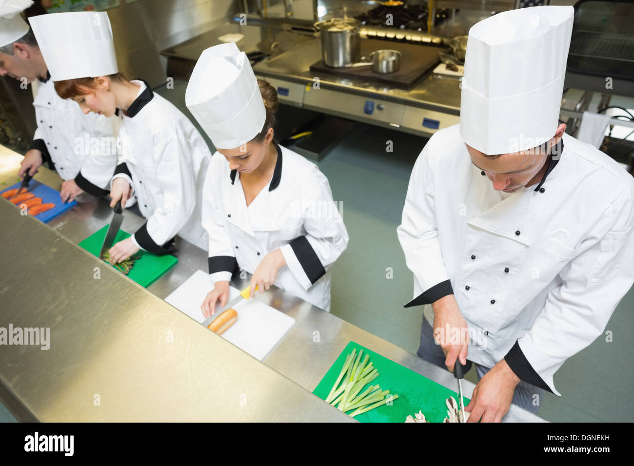 Four chefs preparing food at counter Stock Photo