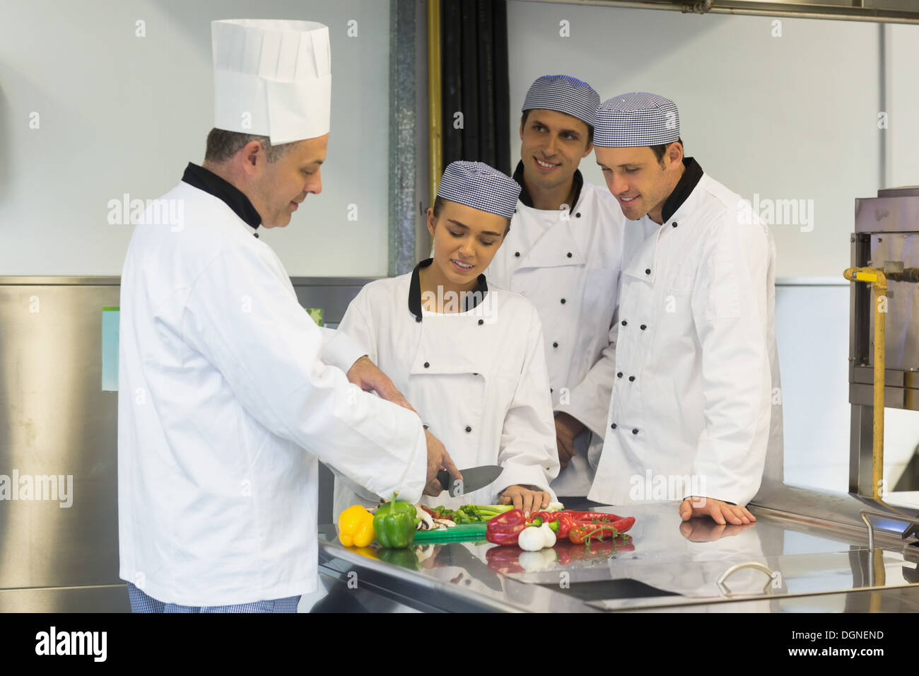 Smiling head chef teaching how to slice vegetables Stock Photo